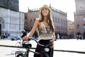 Italy, Bologna, portrait of fashionable young woman pushing bicycle in the city photo